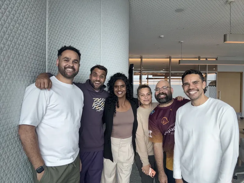 Six people smiling together in an office.