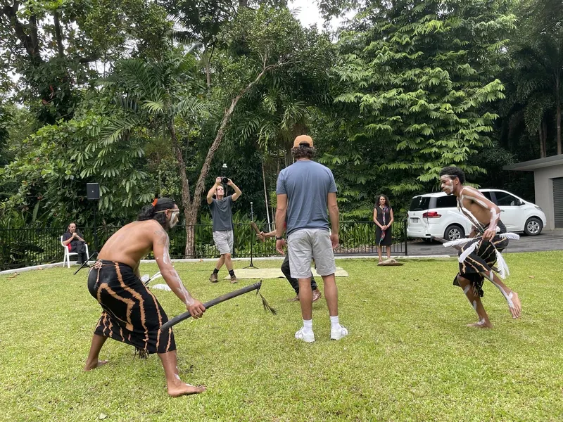 Dancers in body paint perform on a lawn as people look on.
